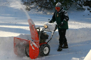 snow blower removing snow and ice in freezing temperature